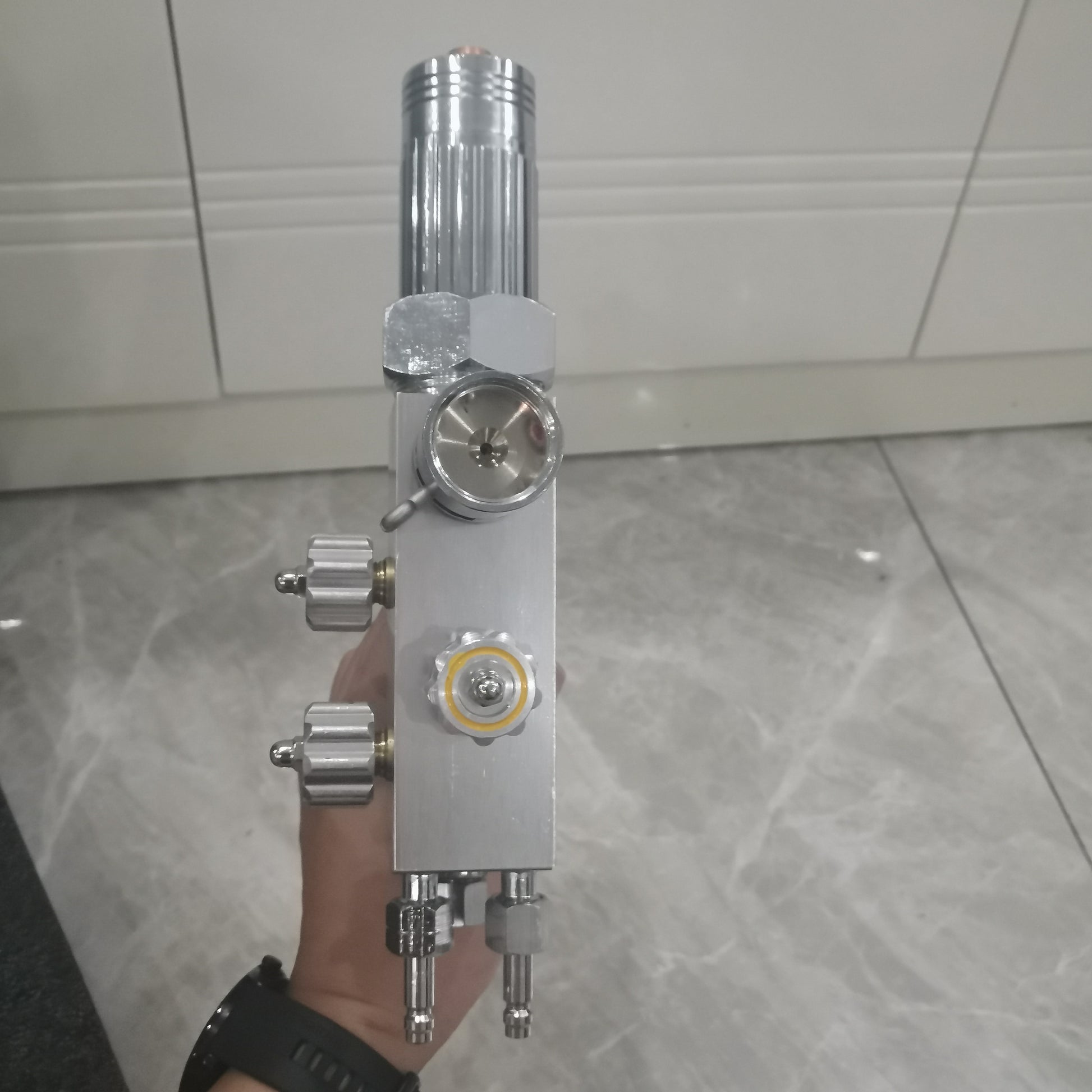 Metal powder spray welding torch side view with yellow control knob and gas ports