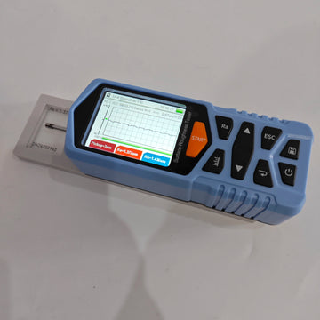 Portable surface roughness tester displaying Ra and Rq profile measurement graph