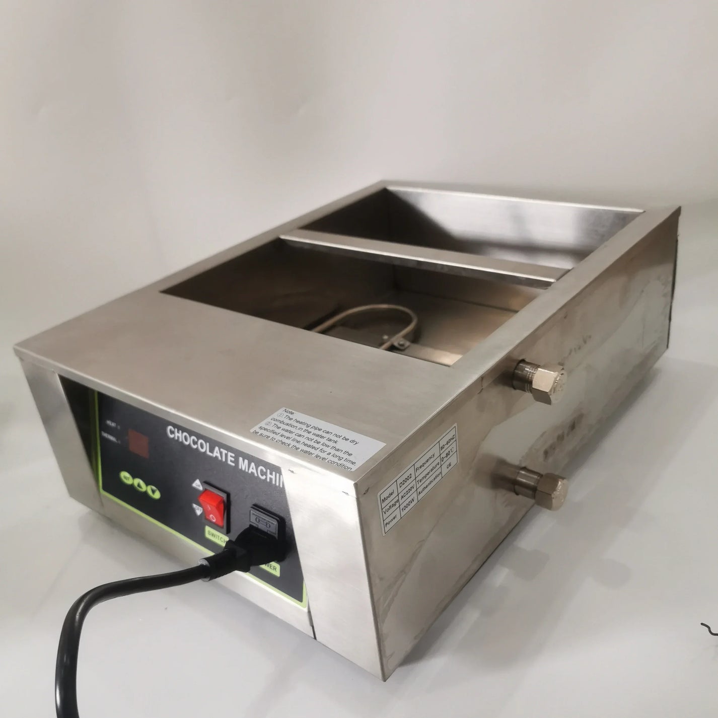 Side view of chocolate melting machine with drain valves and power cord