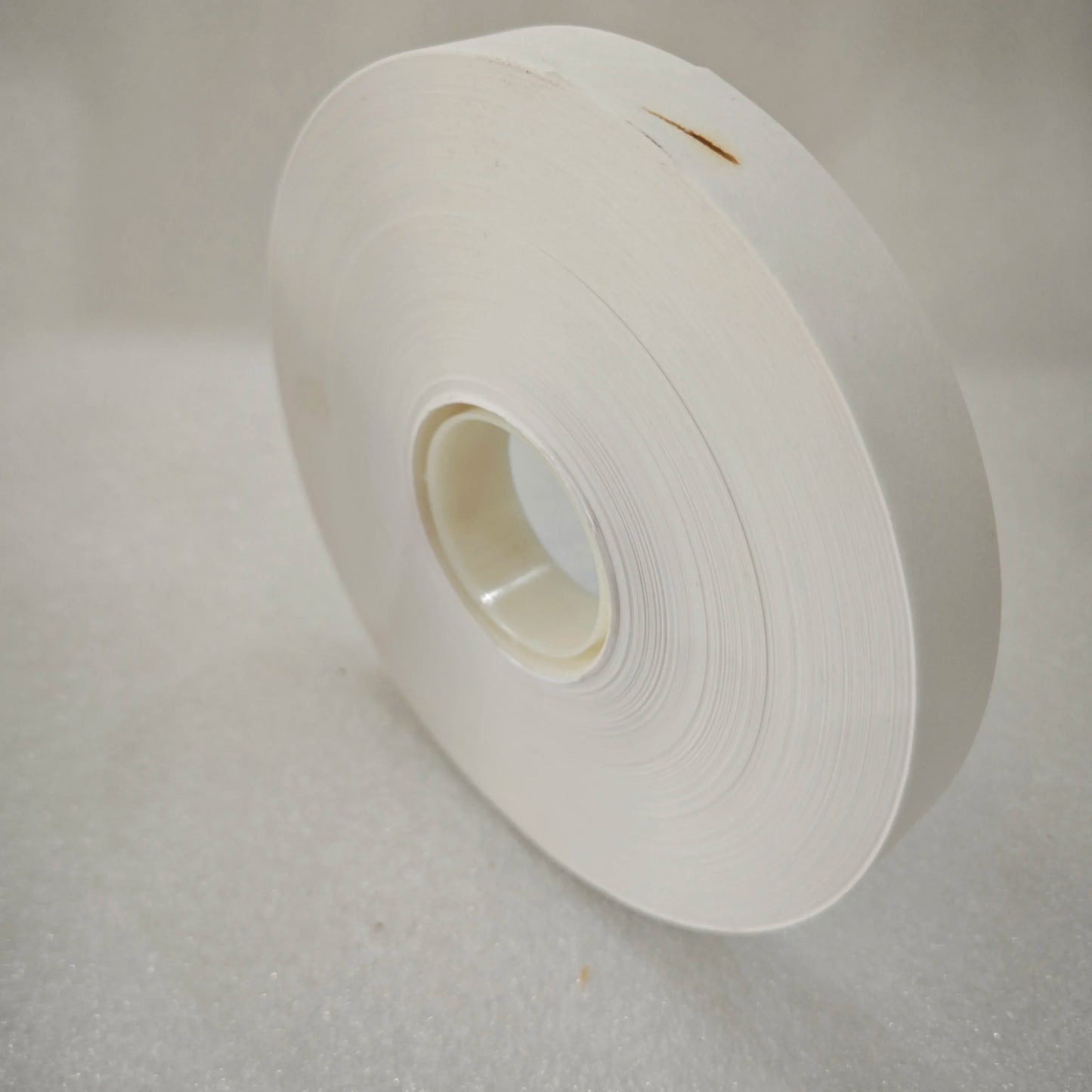 Side view of white paper banding tape roll showing roll thickness