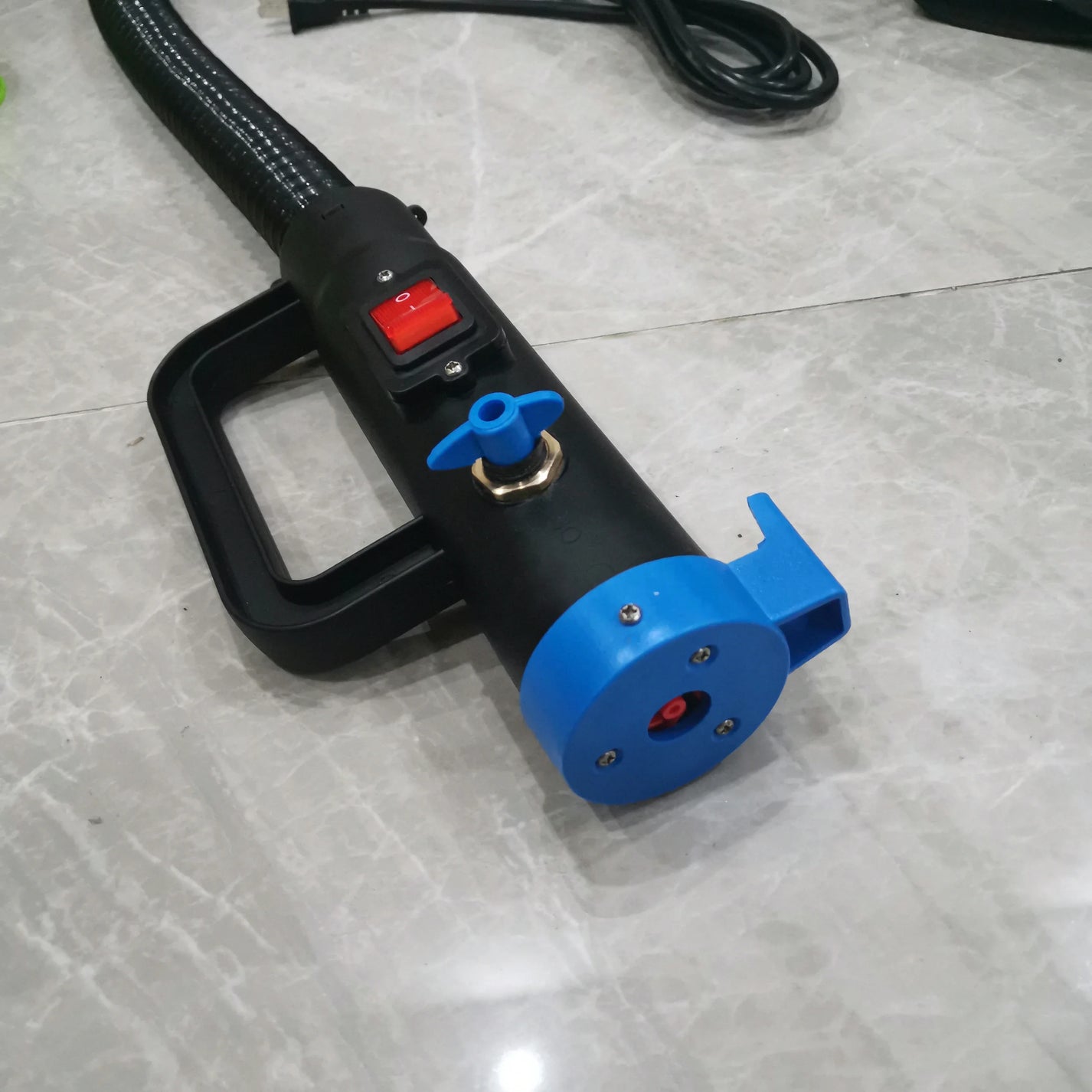 Handheld fogging head with red power switch, blue nozzle end and corrugated hose