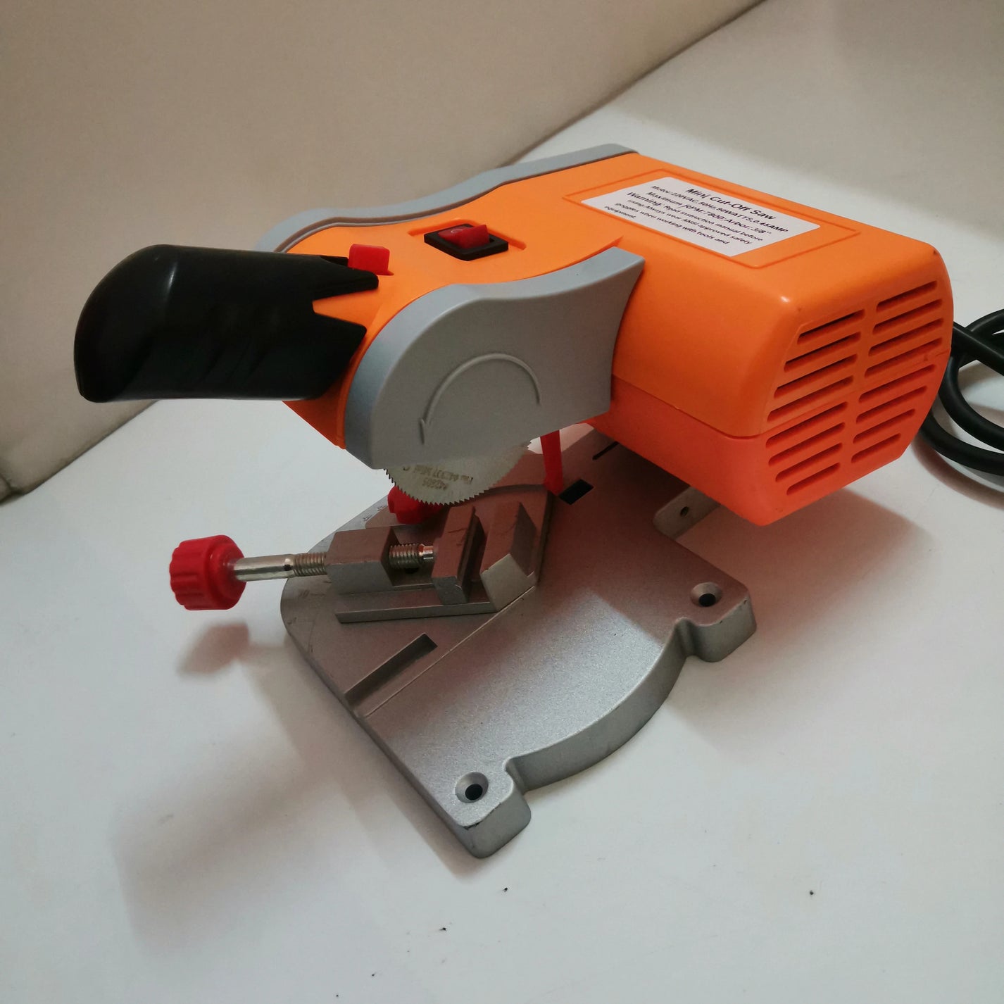 90W mini cut-off saw showing blade guard, vise clamp, and table base