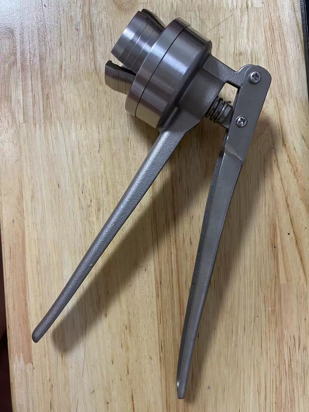 Stainless steel manual vial cap crimper on wood surface